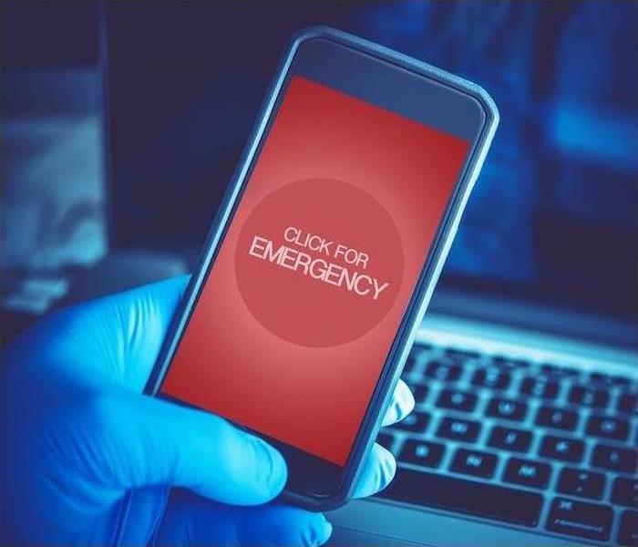 cell phone held over a computer clicking for an emergency